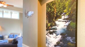 A living room with a large painting of a waterfall, a wooden bowl, and a candle on a mantelpiece. - Eagle Crest Retreat, HOT TUB, Dogs OK, EV Charger (Redmond)