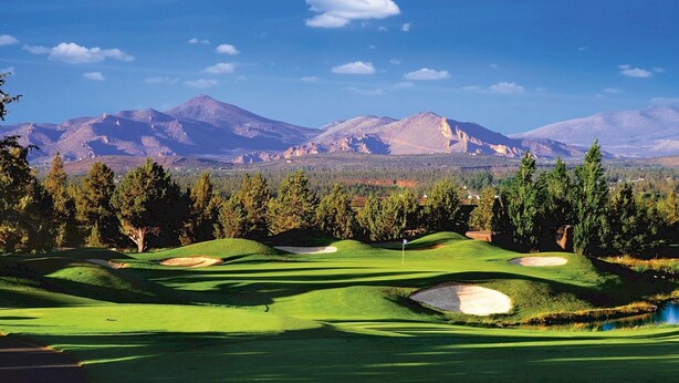 A golf course with rolling green hills, sand bunkers, and a backdrop of mountains. - Eagle Crest Retreat, HOT TUB, Dogs OK, EV Charger (Redmond)