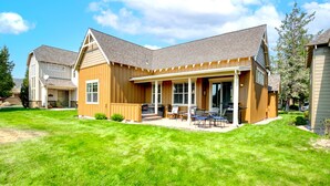 A two-story house with a covered patio, a lawn, and a garage. - Eagle Crest Retreat, HOT TUB, Dogs OK, EV Charger (Redmond)
