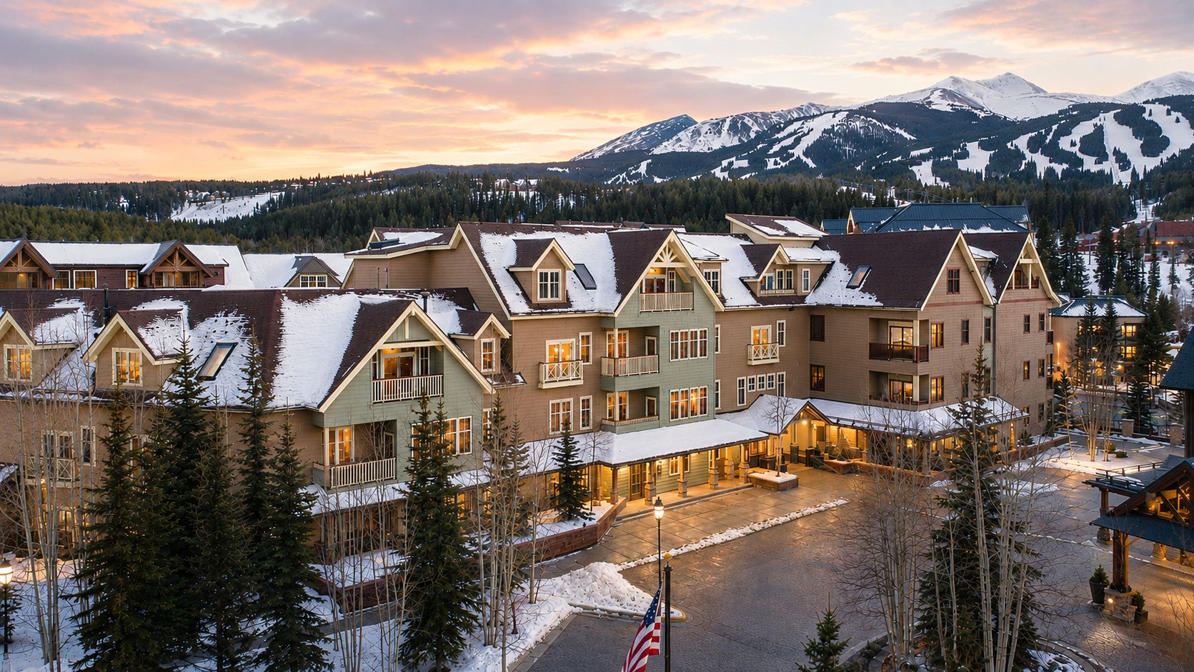 Un hôtel comprenant plusieurs bâtiments, un espace extérieur abrité et offrant une vue sur des montagnes enneigées.