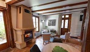 A cozy living room with a fireplace, a sofa set, and a dining table.