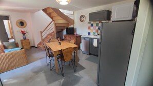 A compact kitchen with a dining table, chairs, a refrigerator, a microwave, and a small sink. - LA Chaira - Neufmanil (NEUFMANIL)