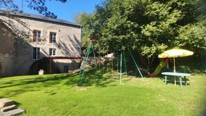 A stone building with a swing set, slide, and picnic table in a backyard. - LA Chaira - Neufmanil (NEUFMANIL)
