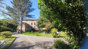 Stroll through the beautifully manicured lawn surrounded by mature trees, including a prominent maple.