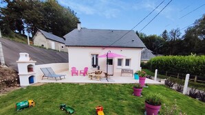 Ein Haus mit Terrasse, Sitzgelegenheit im Freien und einem kleinen Garten.