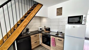 Eine kompakte Küche mit einer Holztreppe, einem eingebauten Geschirrspüler, einer Mikrowelle und einem Kühlschrank.
