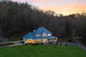 A two-story house with a blue roof, surrounded by a forest. - Spacious Murphy Home w/ Game Room + Fire Pit! (Murphy)