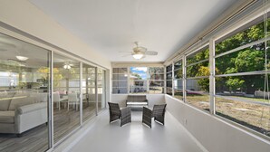 Ein modernes Interieur mit einer Glaswand, einem Deckenventilator und Blick ins Freie.