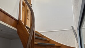 A wooden spiral staircase with carpeted steps and a metal handrail. - Gemütliche Ferienwohnung im Grünen (Alsfeld)
