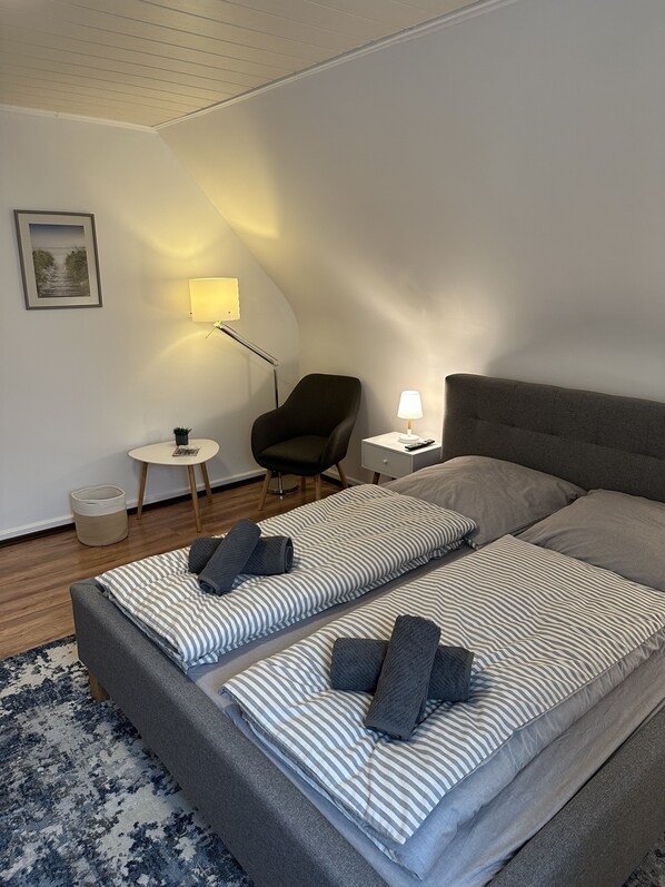 Ein modernes Hotelzimmer mit einem großen Bett, einem Sessel, einem kleinen Tisch und einer Lampe.
