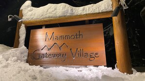 A wooden sign with the text "Mammoth Gateway Village" surrounded by snow.