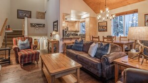A cozy living room with a wooden ceiling, a leather sofa, and a dining area with a table and chairs.