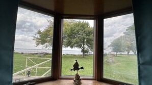 Une baie vitrée donnant sur un espace verdoyant, un arbre et une étendue d’eau.