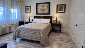 Una camera da letto ordinata con un letto grande, due comodini con lampade, un termosifone e quadri appesi alle pareti.