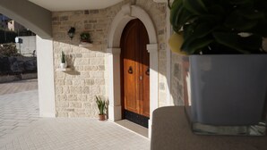 A stone building entrance with a wooden door, potted plants, and a tiled floor. - Elegant standard room in Riccia (Molise)