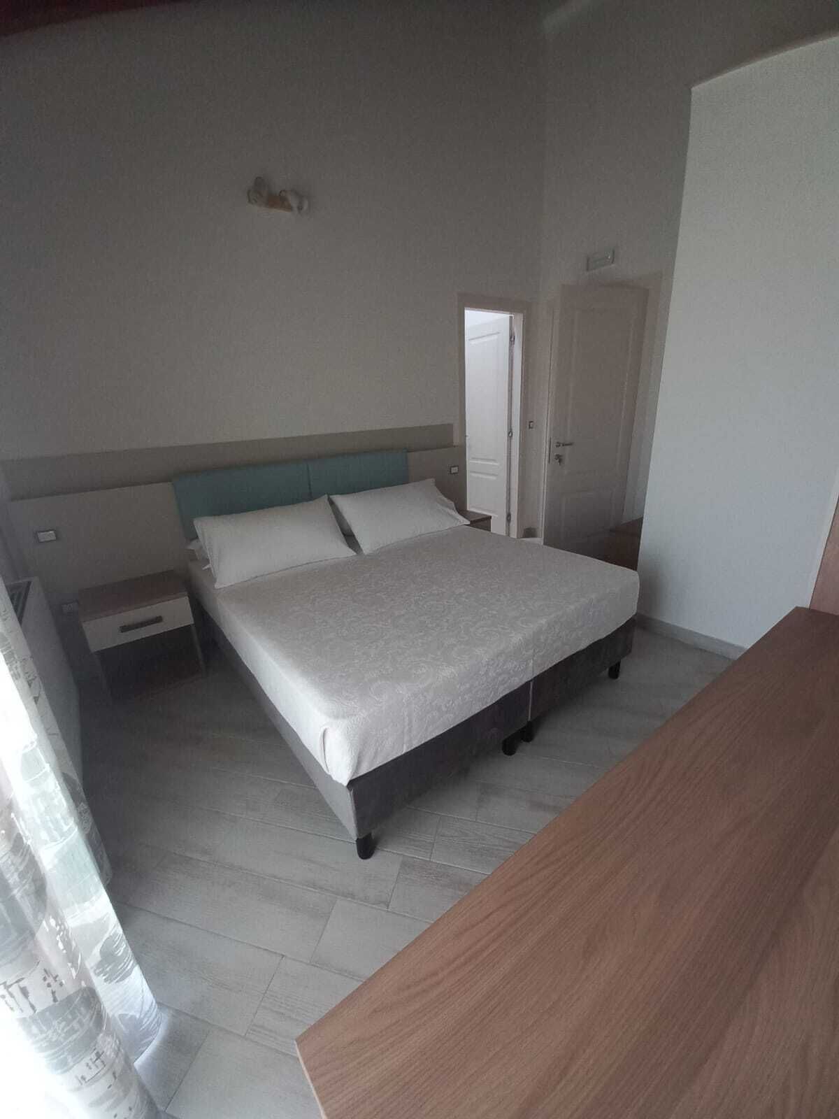 A bedroom with a bed, a nightstand, a wooden dresser, and a door.