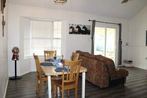 Relax in this open-plan living space with a dining area and seating area, featuring a wooden table and comfortable sofa.