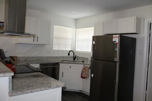 Enjoy cooking in this well-equipped kitchen with a refrigerator, dishwasher, and granite countertop.