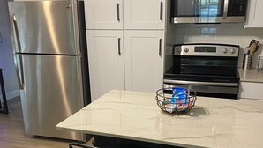 Een moderne keuken met witte kastjes, roestvrijstalen apparatuur en een marmeren aanrecht.