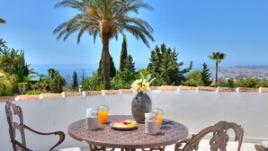 A round table with a vase of yellow flowers, two cups, and a plate of fruit. - Colina del Mar, un Magnífico Jardín con Piscina y Maravillosas Vistas (Benalmádena)