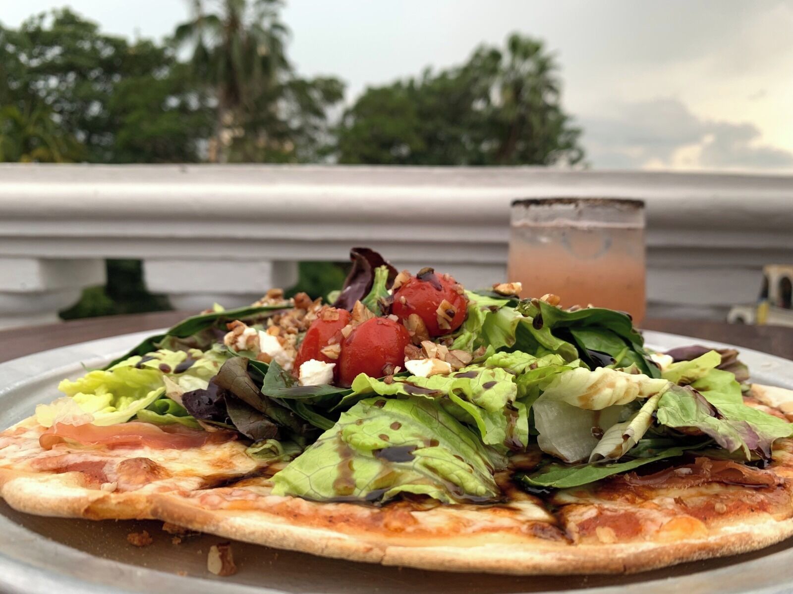 Una pizza con una ensalada sobre un plato de metal.