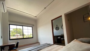 A bedroom with a bed, a desk, and a chair. There is a window providing natural light. - C. Santos Degollado 34 (Colima)