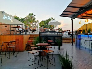 An outdoor patio area with tables and chairs, a pool, and a bar area. - C. Santos Degollado 34 (Colima)