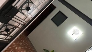 A room with a patterned floor, a potted plant, a wall-mounted light fixture, and a small window. - C. Santos Degollado 34 (Colima)