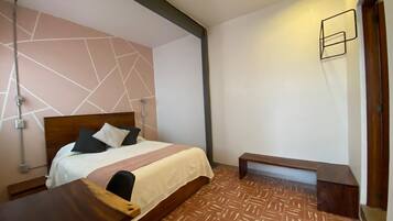 Une chambre d’hôtel avec un lit, une table de chevet et un banc.