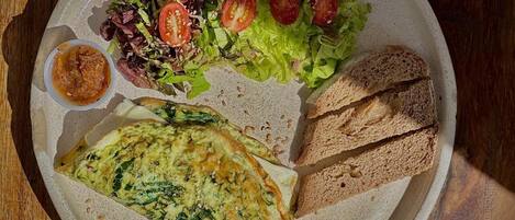 A plate with a salad, bread, and a rolled omelette.
