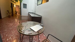 A small, enclosed patio area with a round glass table and chairs, a small sink, and potted plants. - C. Santos Degollado 34 (Colima)