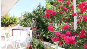 A garden with a white pergola, a stone wall, and a variety of plants. - Holiday apartment mit Terrasse und Klimaanlage (Šilo)
