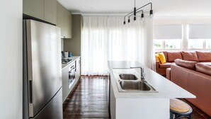 A modern kitchen with a central island, stainless steel appliances, and a dining area with a brown leather sofa.