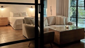 A modern bedroom with a bed, two chairs, a coffee table, and a large window with curtains. - Risco de Hugo (Boquete)