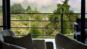 A room with a large window overlooking a mountainous landscape. - Risco de Hugo (Boquete)