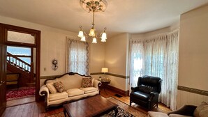 Uma sala de estar com sofá, poltrona de couro, mesa de centro de madeira e tapete estampado.