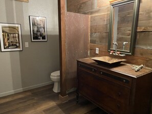 A bathroom with a wooden vanity, a sink, and a toilet. There are framed pictures on the wall. - 3547 Pleasant Run Rd (Heltonville)