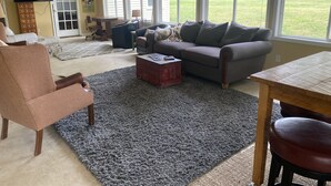 Un salon comprenant un canapé, un fauteuil, une table basse et un téléviseur fixé au mur.
