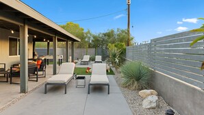 An outdoor patio with lounge chairs, a barbecue grill, and a small table. - The Hidalgo House (Desert Hot Springs)