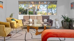 A modern living room with a glass coffee table, a sofa, and two armchairs. - The Hidalgo House (Desert Hot Springs)