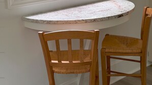Una cocina con una isla integrada, dos sillas de madera y una ventana con vista a un jardín.