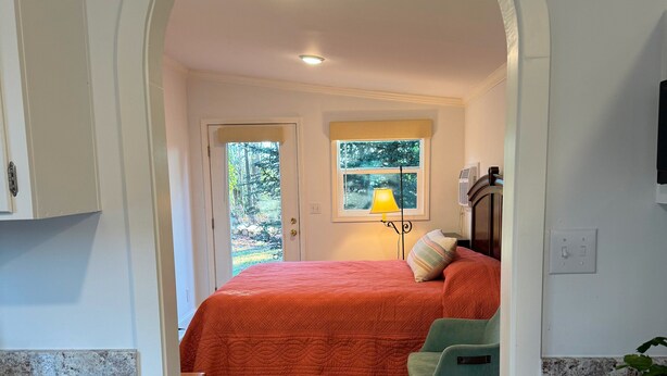 Un dormitorio con cama, ventana, lámpara y escritorio.