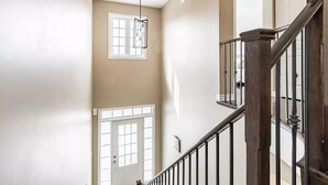 A staircase with a wooden handrail and metal balusters, leading to a landing with a door and a window. - Spacious and Comfortable House near Squireband (Mississauga)