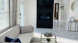 Una sala de estar moderna con un sofá, una mesa de centro de vidrio y una chimenea.