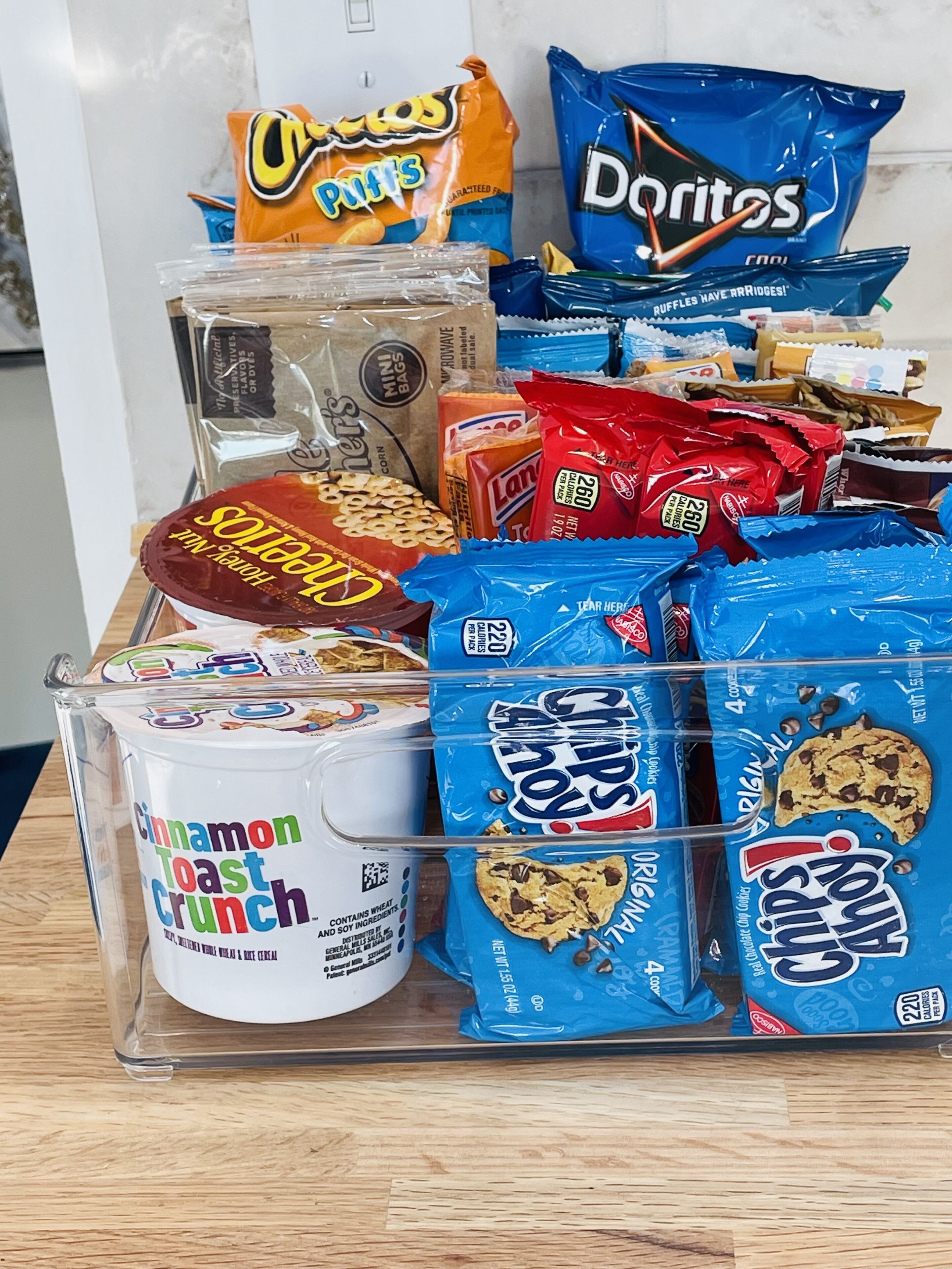 A variety of snacks including chips, cookies, and a tub of cinnamon toast crunch.