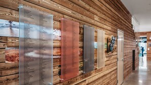 A wooden wall with multiple nameplates displaying lists of names and prices. - Fir Tree House 307 (Traverse City)