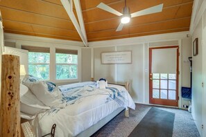 A bedroom with a bed, a ceiling fan, a door, and a window.