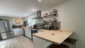 Uma cozinha moderna com eletrodomésticos de aço inoxidável, bancadas de madeira e prateleiras embutidas.