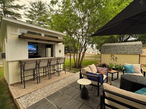 An outdoor patio with a bar area, seating, and a small shed.
