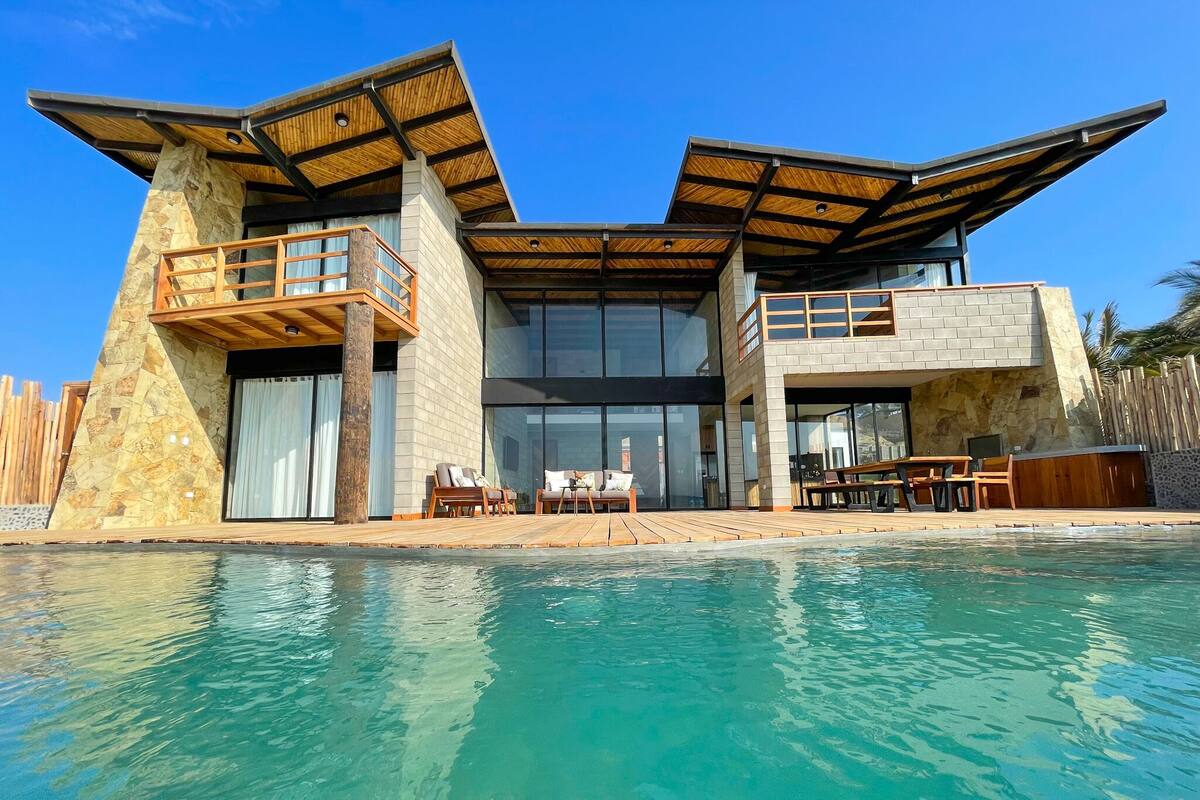 Une maison moderne à deux étages avec une piscine à l’avant.